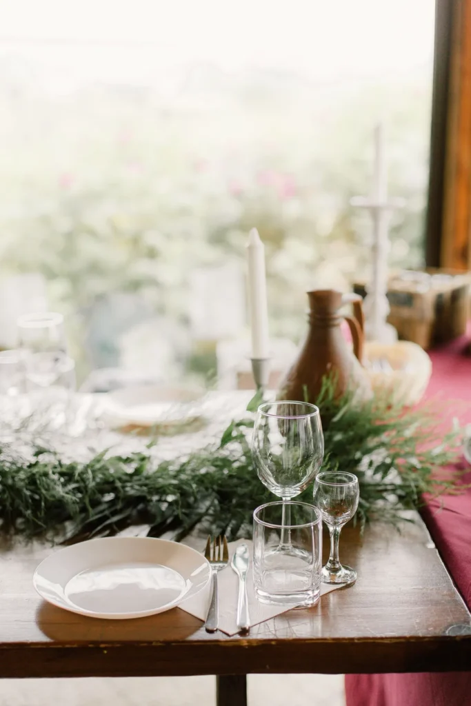 Warm white plates, napkins, and candles set on a small Thanksgiving table