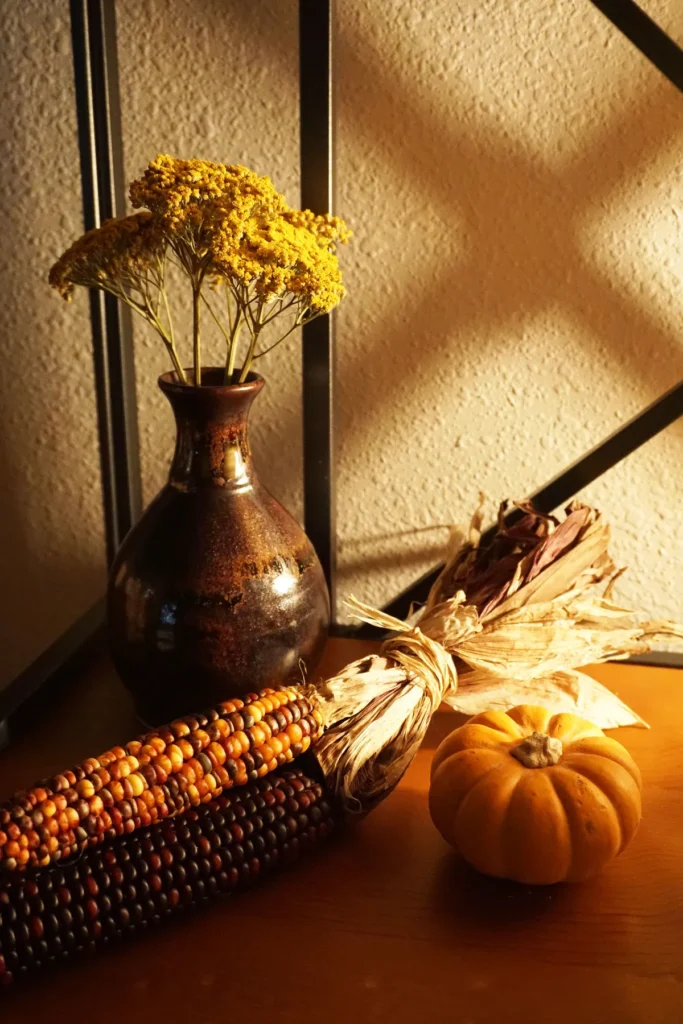 Small vase of fall leaves and mini pumpkins as a simple Thanksgiving table decoration